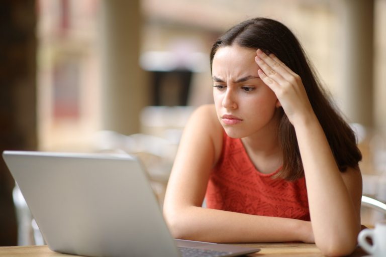 Teenager looking at laptop confused